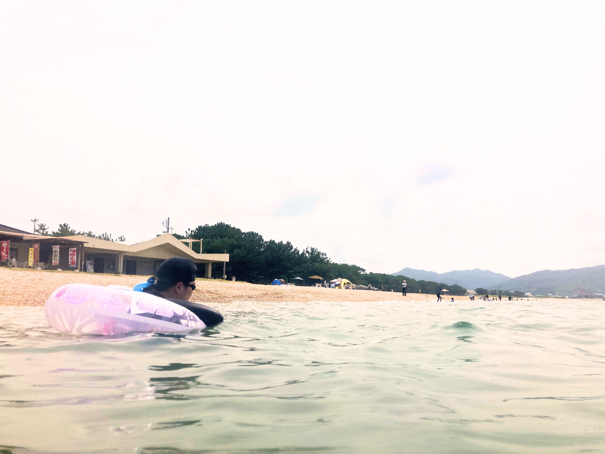 浮き輪で笑顔のJ君（後ろ姿）＋海と青空