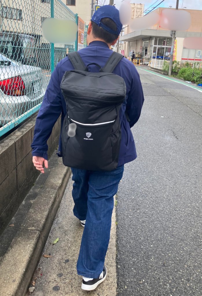 黒いリュックを背負って歩く息子の後ろ姿